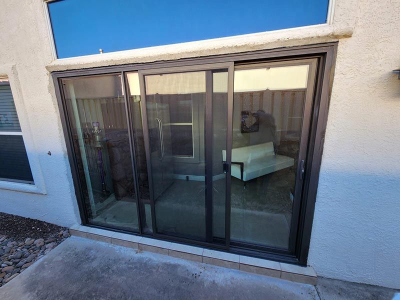 Sliding glass patio doors on a stucco house, showing a living room inside