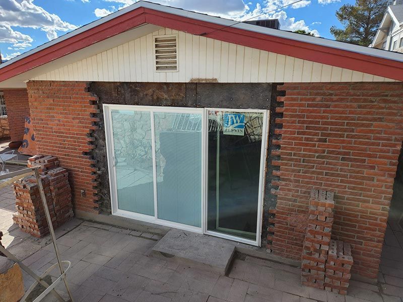 Brick house exterior with a sliding glass door under a red roof.