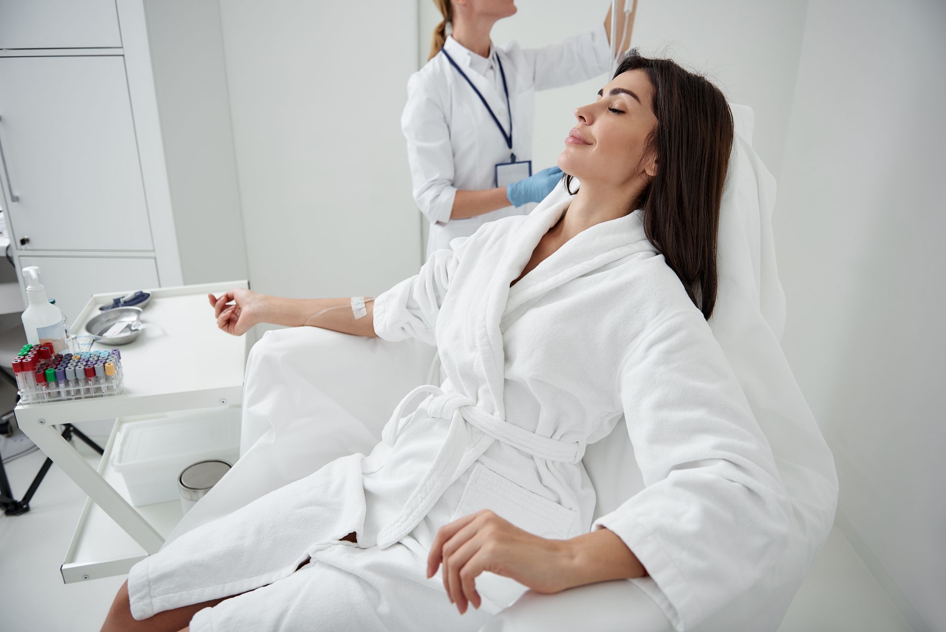 Woman in white robe receiving a facial treatment from a clinician in a bright spa room Woman in white robe receiving a facial treatment from a clinician in a bright spa room