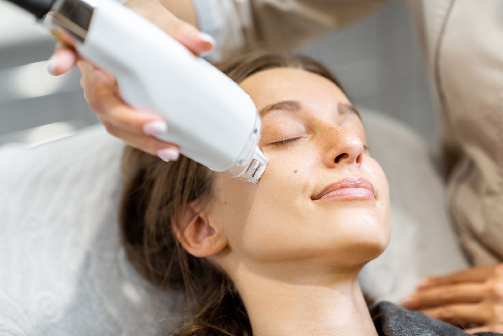 A facial treatment is being applied to a woman's face with a handheld device in a spa setting.