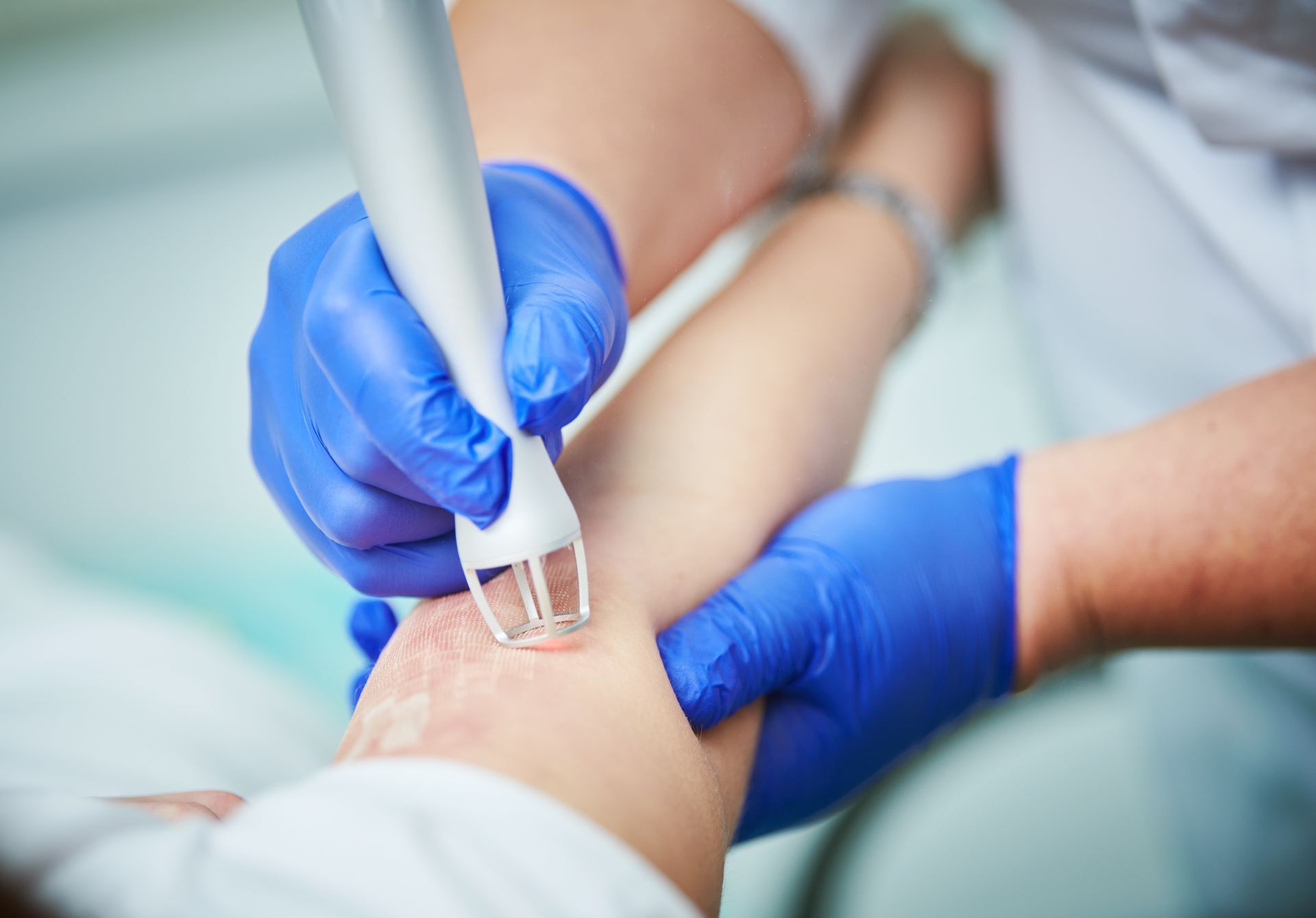 Gloved hands using a medical device on a patient’s arm during a procedure