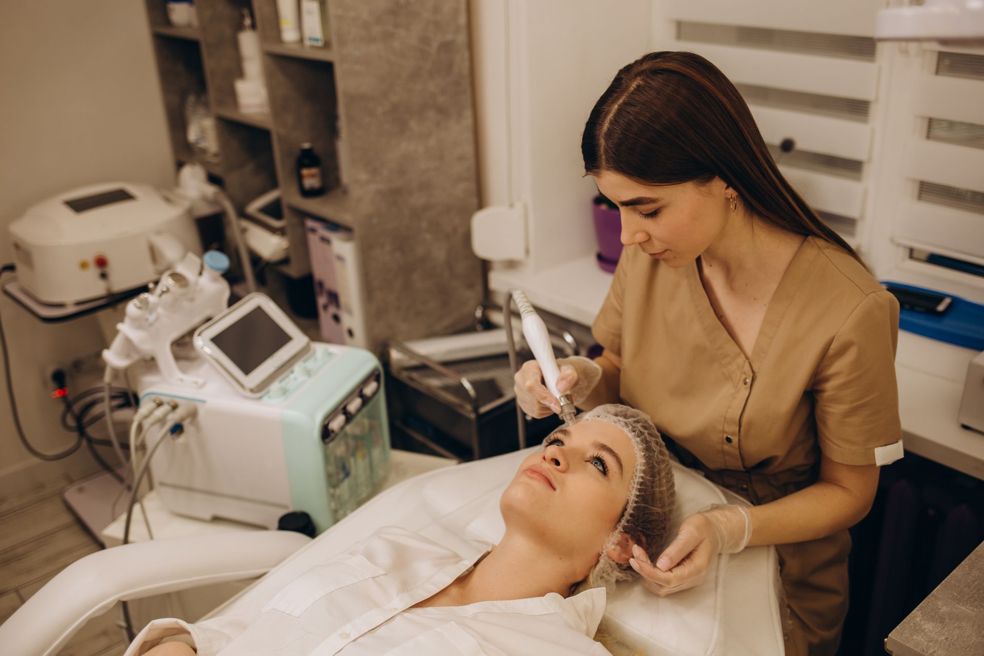 A clinician performs a facial treatment on a patient in a spa treatment room.