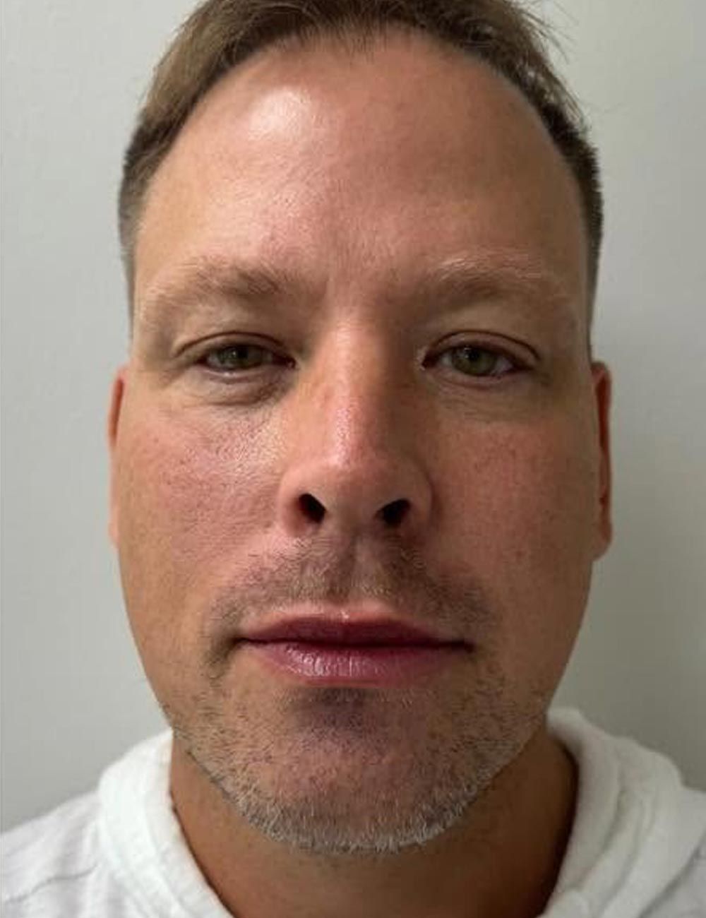 Close-up portrait of a man with a neutral expression against a plain light background