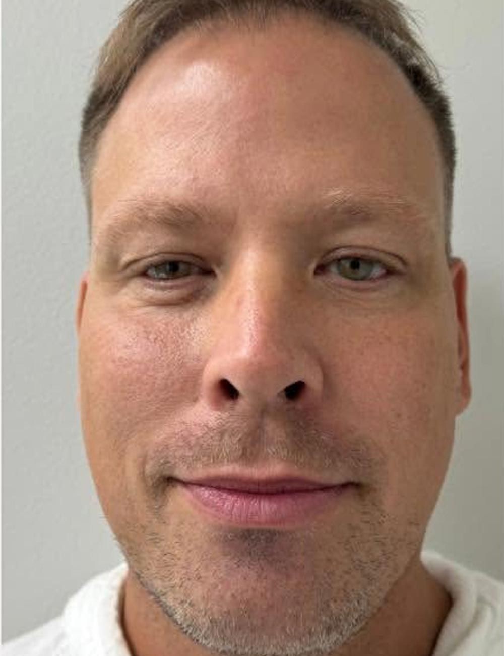 Close-up portrait of a man with a neutral expression against a plain light background
