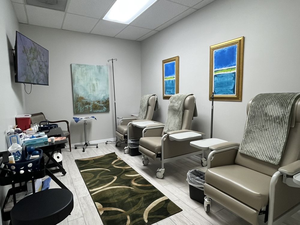 Medical exam room with beige reclining chairs, a patterned rug, and framed wall art