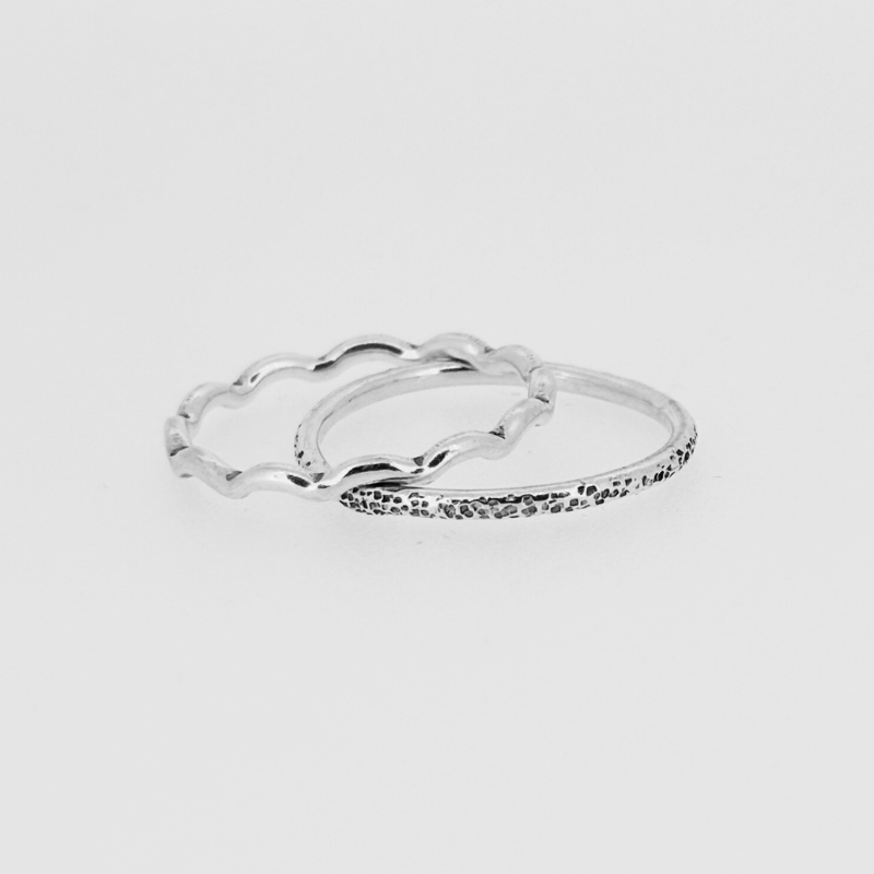 Two silver rings are stacked on top of each other on a white surface.