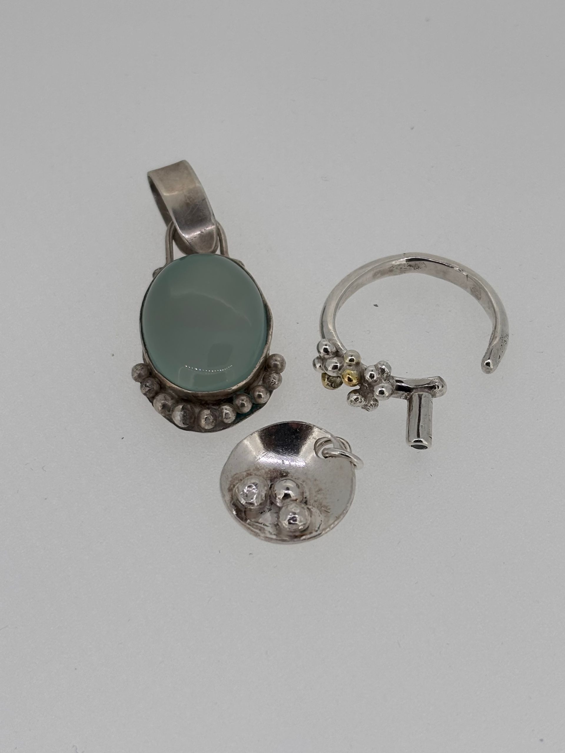 A pendant and a ring are on a white surface
