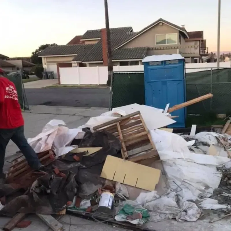 A man in a red shirt is standing in front of a pile of trash