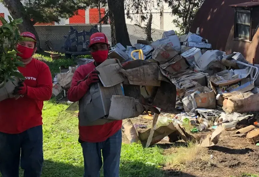 Two people wearing masks are standing in front of a pile of trash.