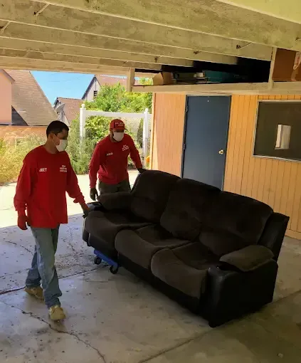 Two men are moving a couch in a garage.
