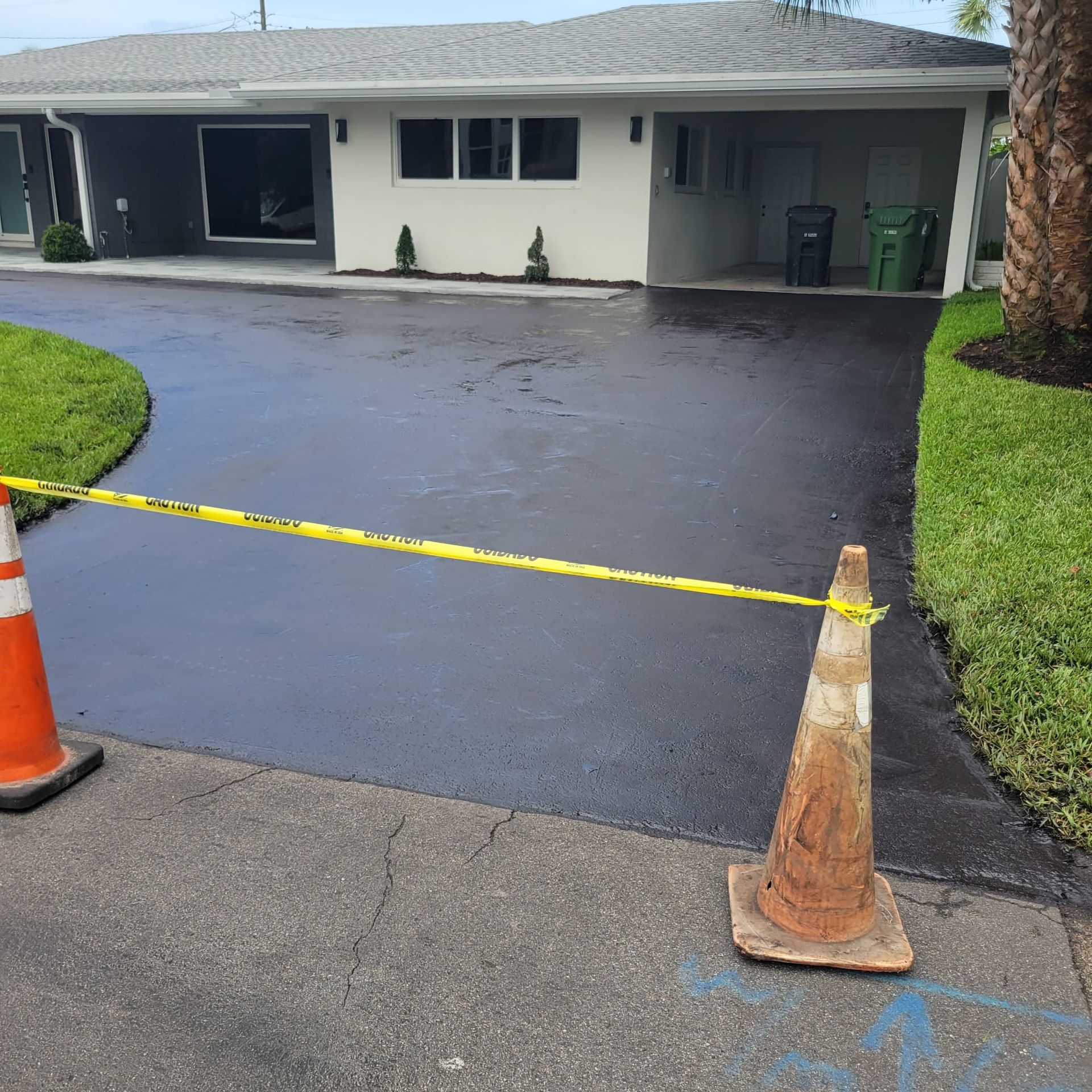 Worker pouring hot asphalt onto a driveway for resealing, ensuring a smooth and durable surface.