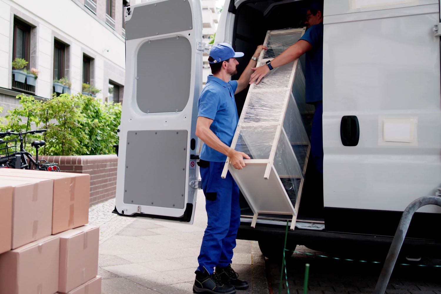 Mover loading furniture into a white van outside a building