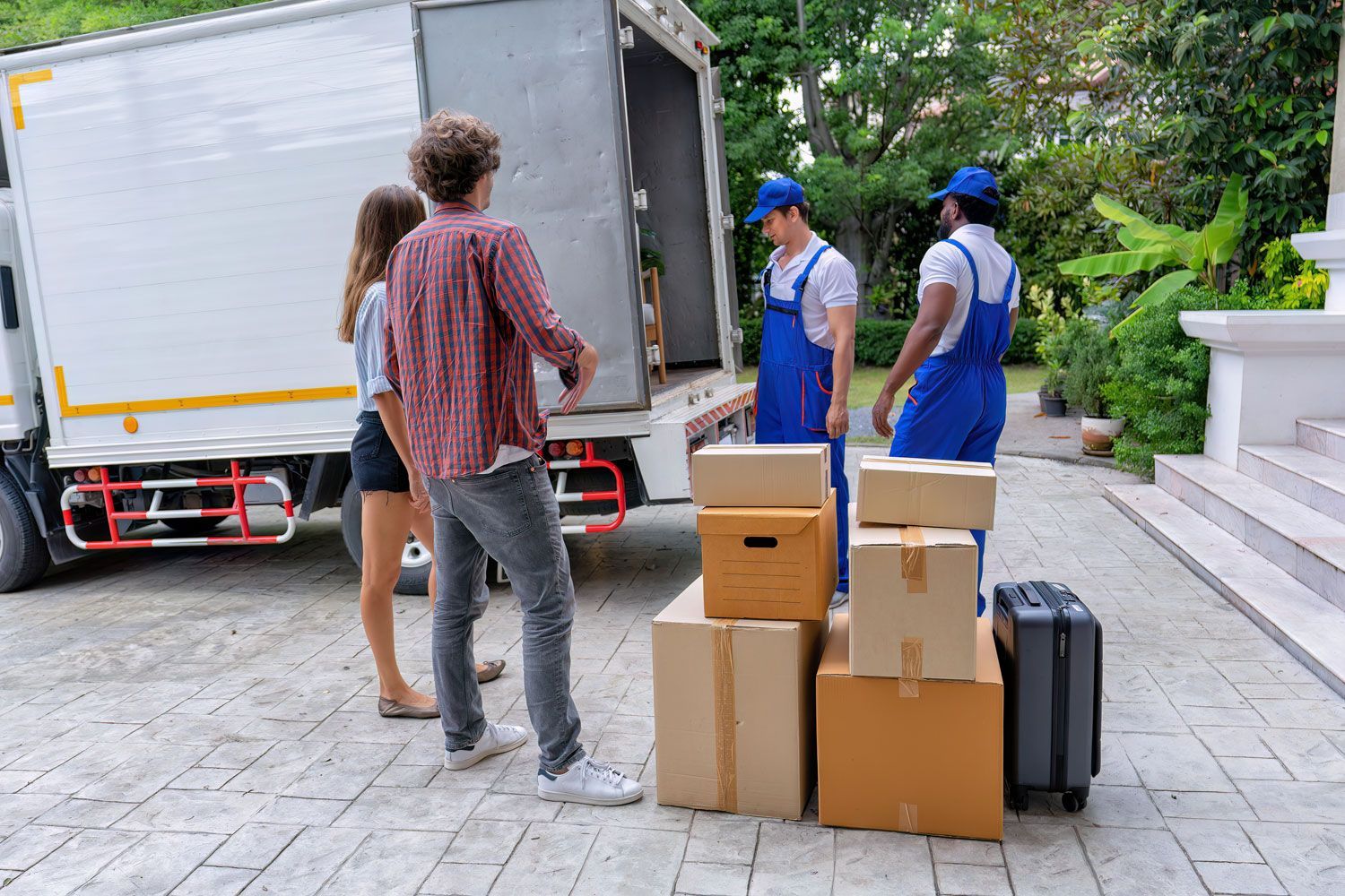 People unloading cardboard boxes from a truck onto a driveway