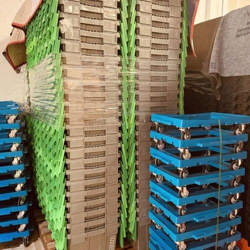 Stacks of blue and green plastic chairs and beige folding tables stored upright in a warehouse.