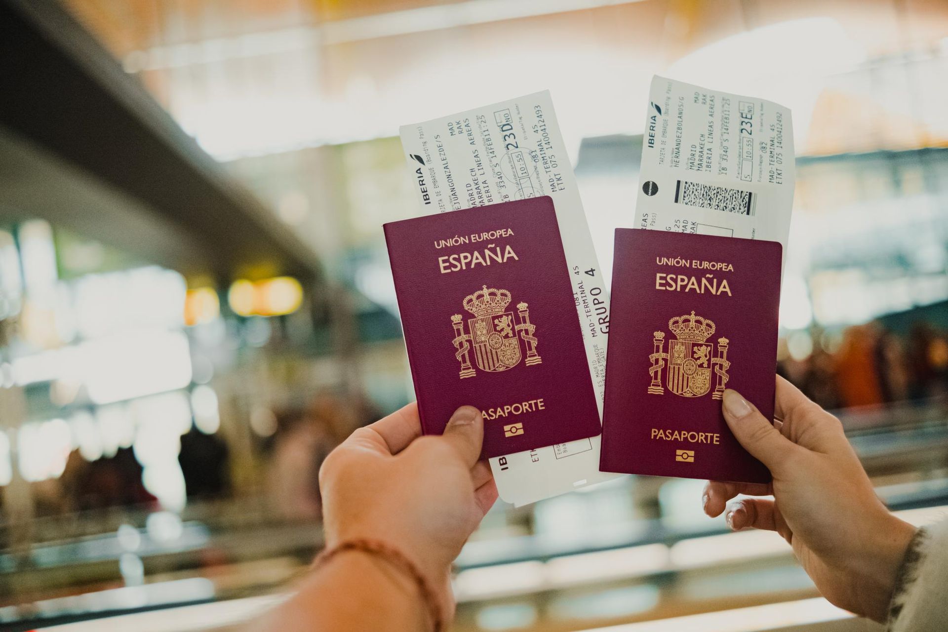 Una persona sostiene dos pasaportes españoles y dos billetes en sus manos.