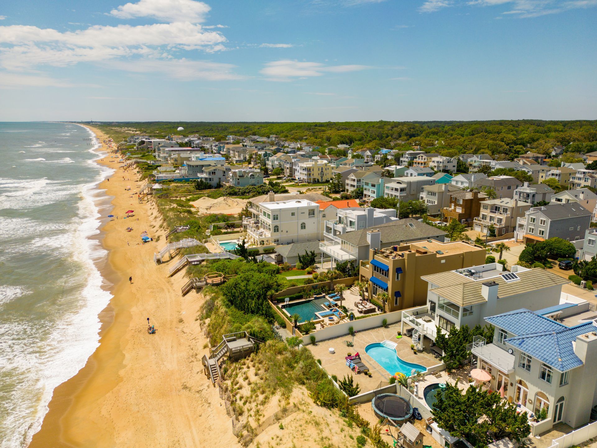 An aerial view of a beach with houses and a pool.