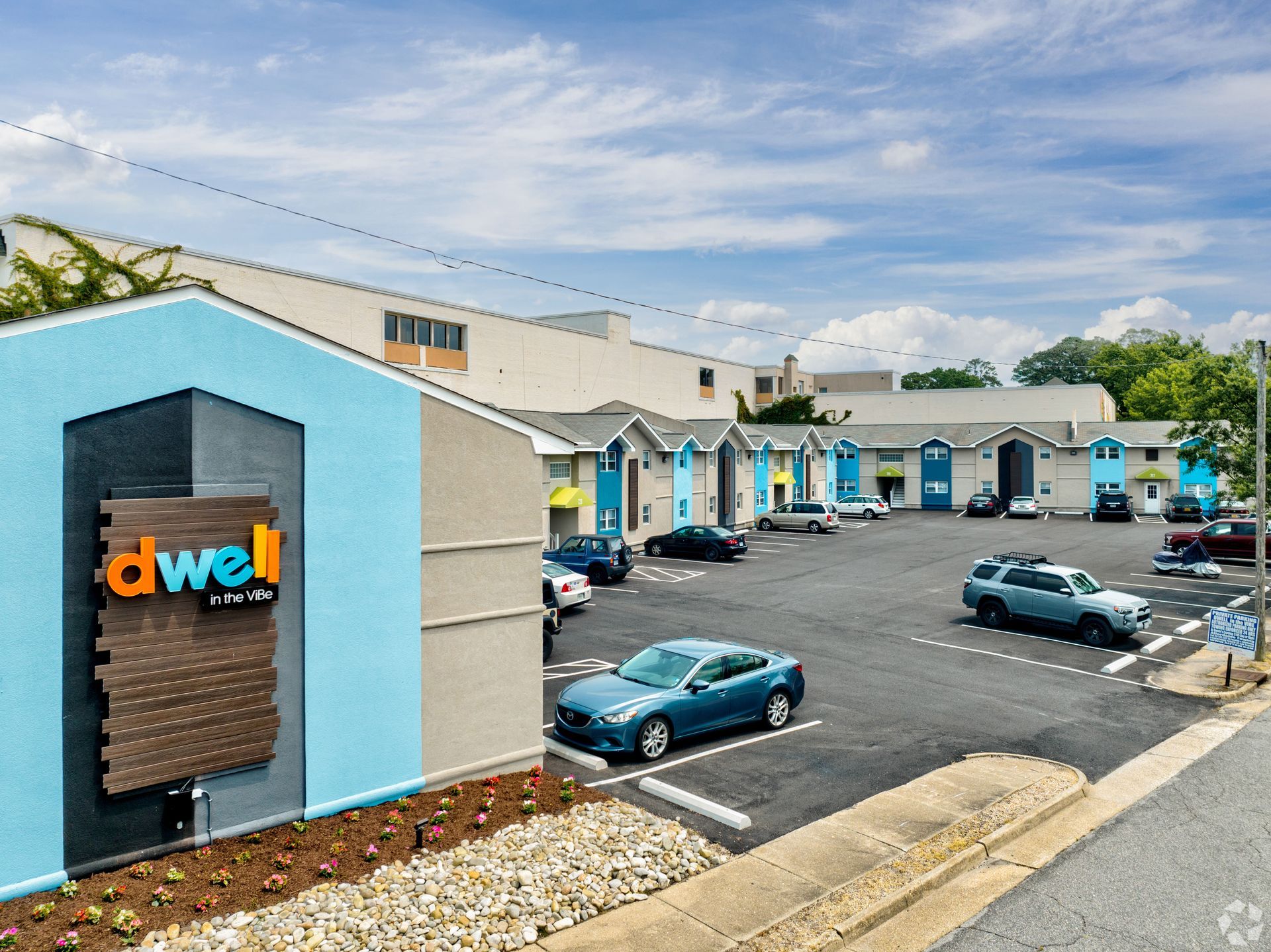 A parking lot with cars parked in front of a building that says dwell