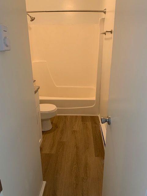 A bathroom with a toilet , tub and shower.
