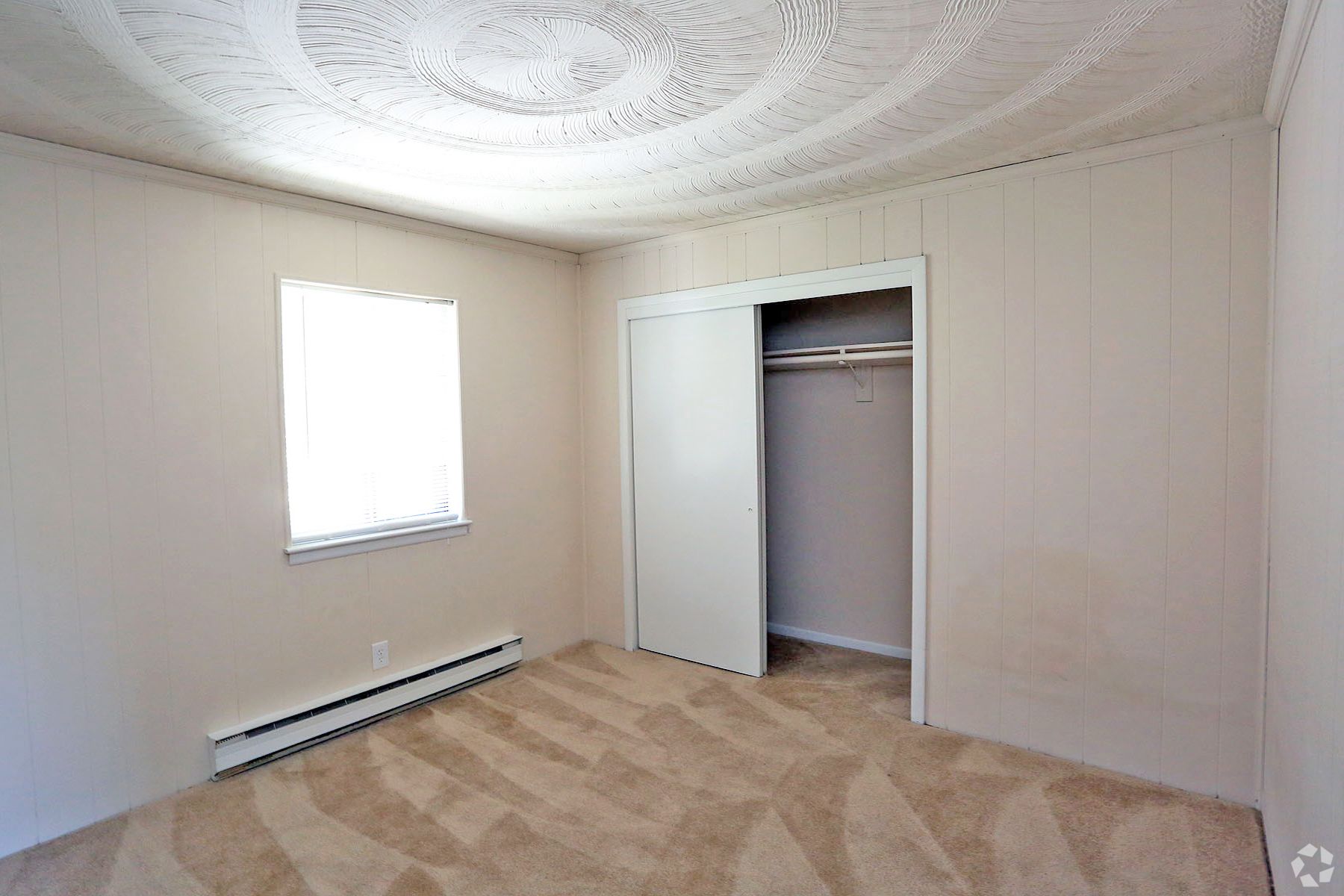 An empty bedroom with a closet and a window.