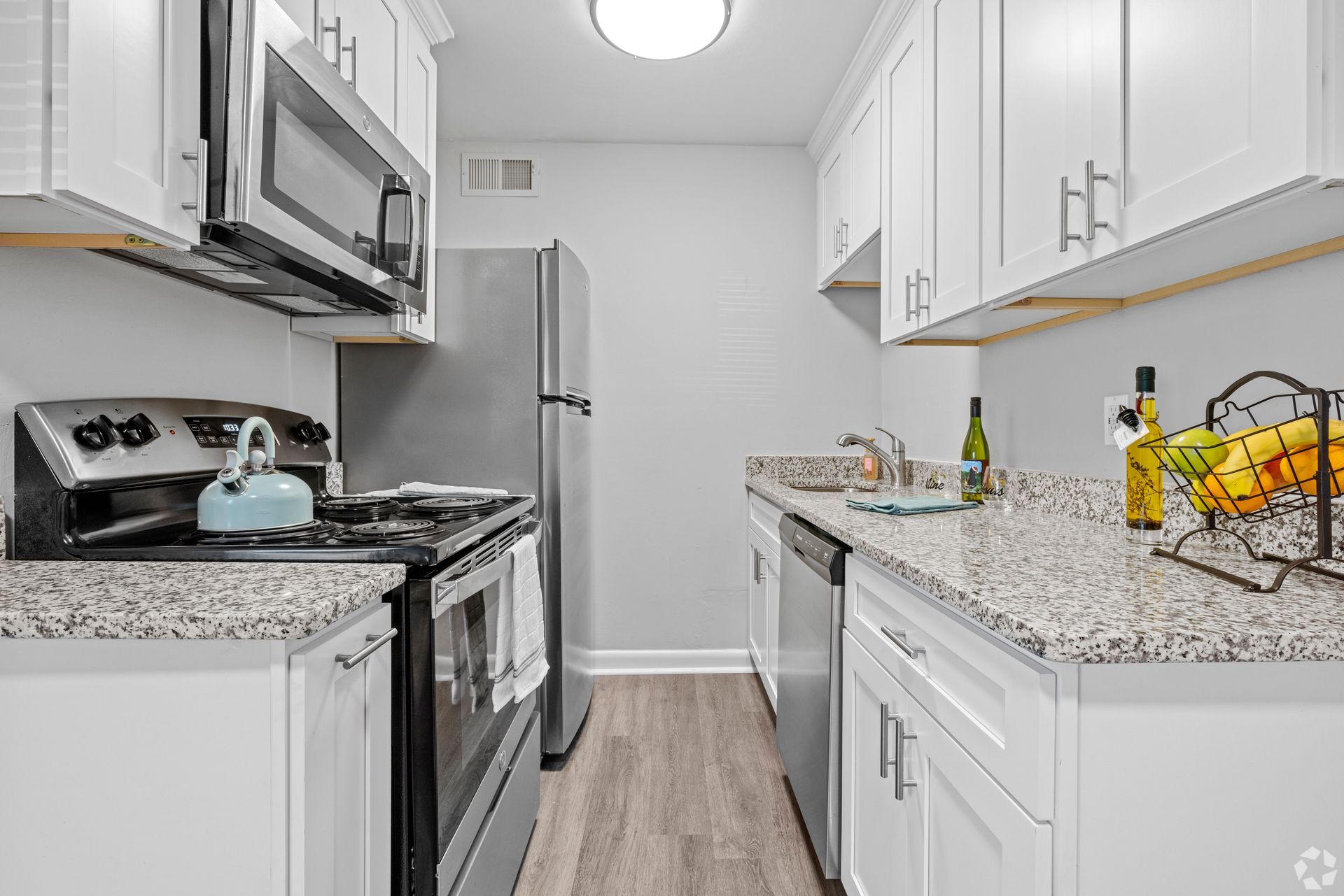 A kitchen with stainless steel appliances , granite counter tops , and white cabinets.