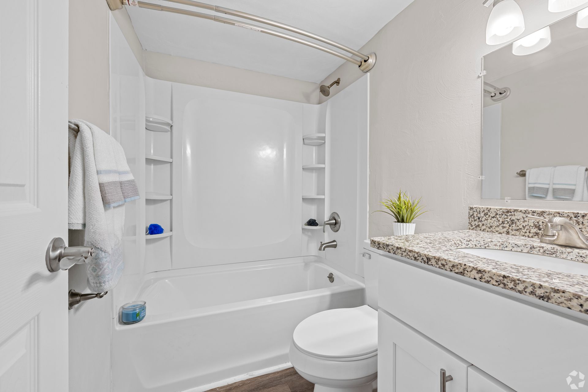 A bathroom with a toilet , sink , bathtub and mirror.