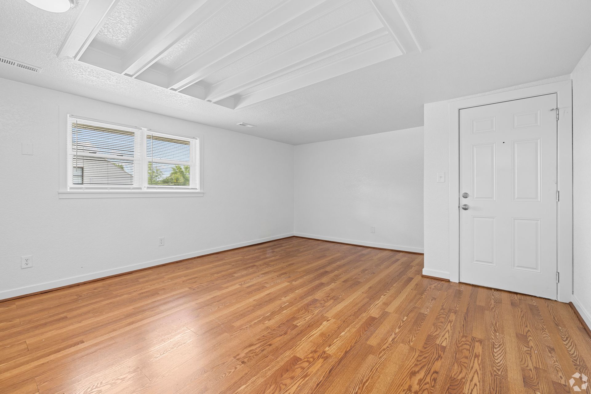 An empty room with hardwood floors and white walls.