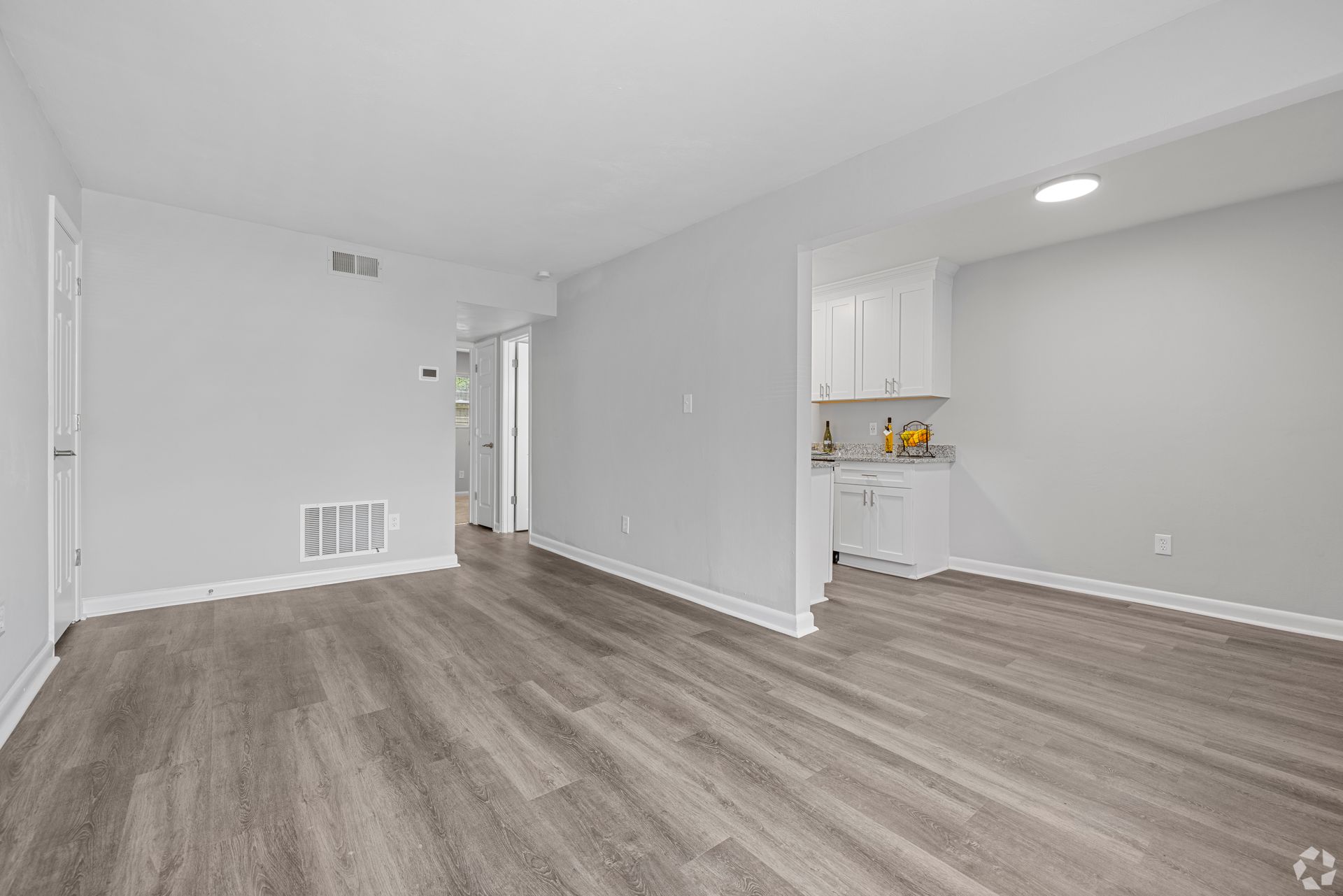 An empty living room with hardwood floors and white walls.