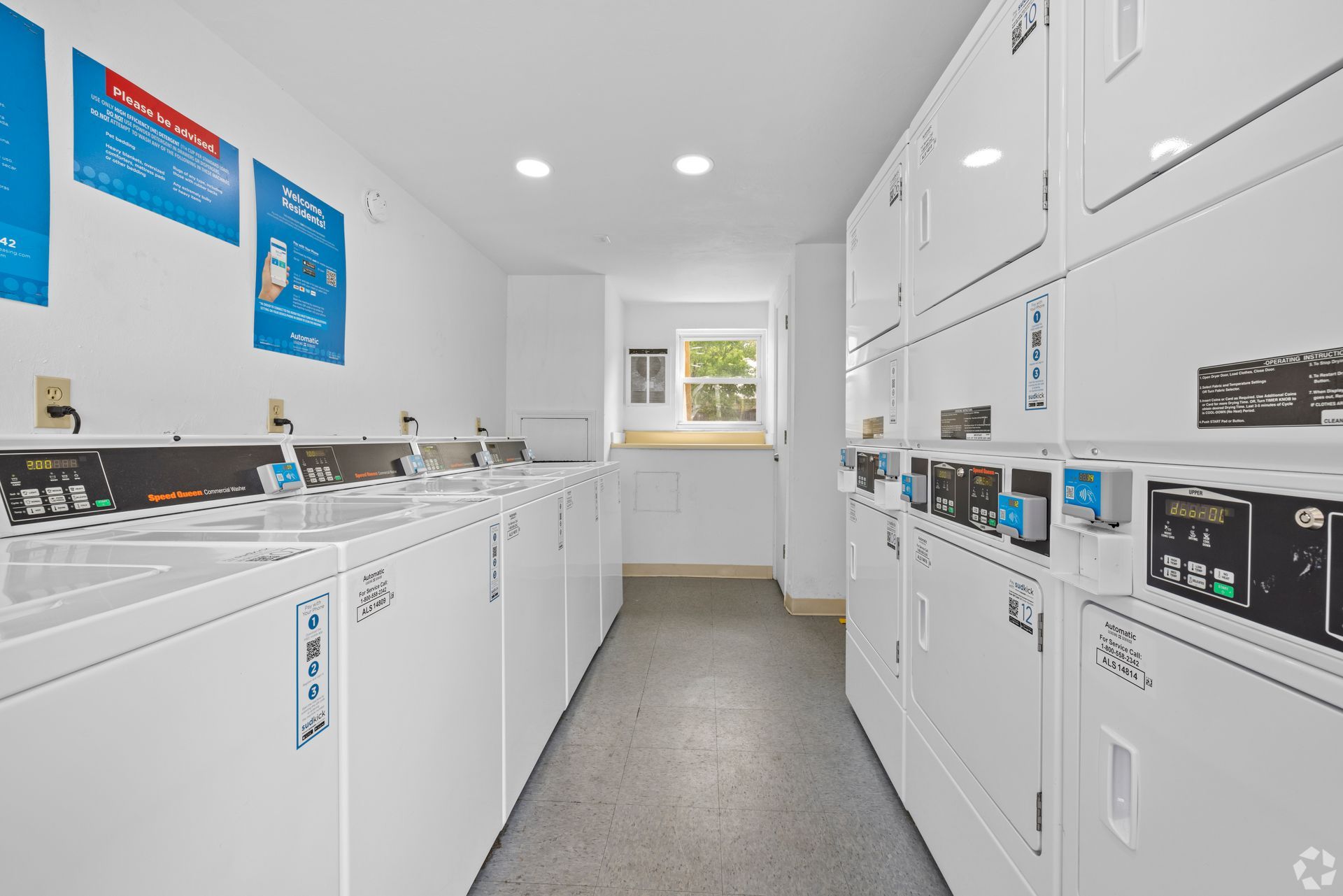 A laundromat filled with lots of white washers and dryers.