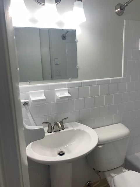 A bathroom with a toilet a sink and a mirror