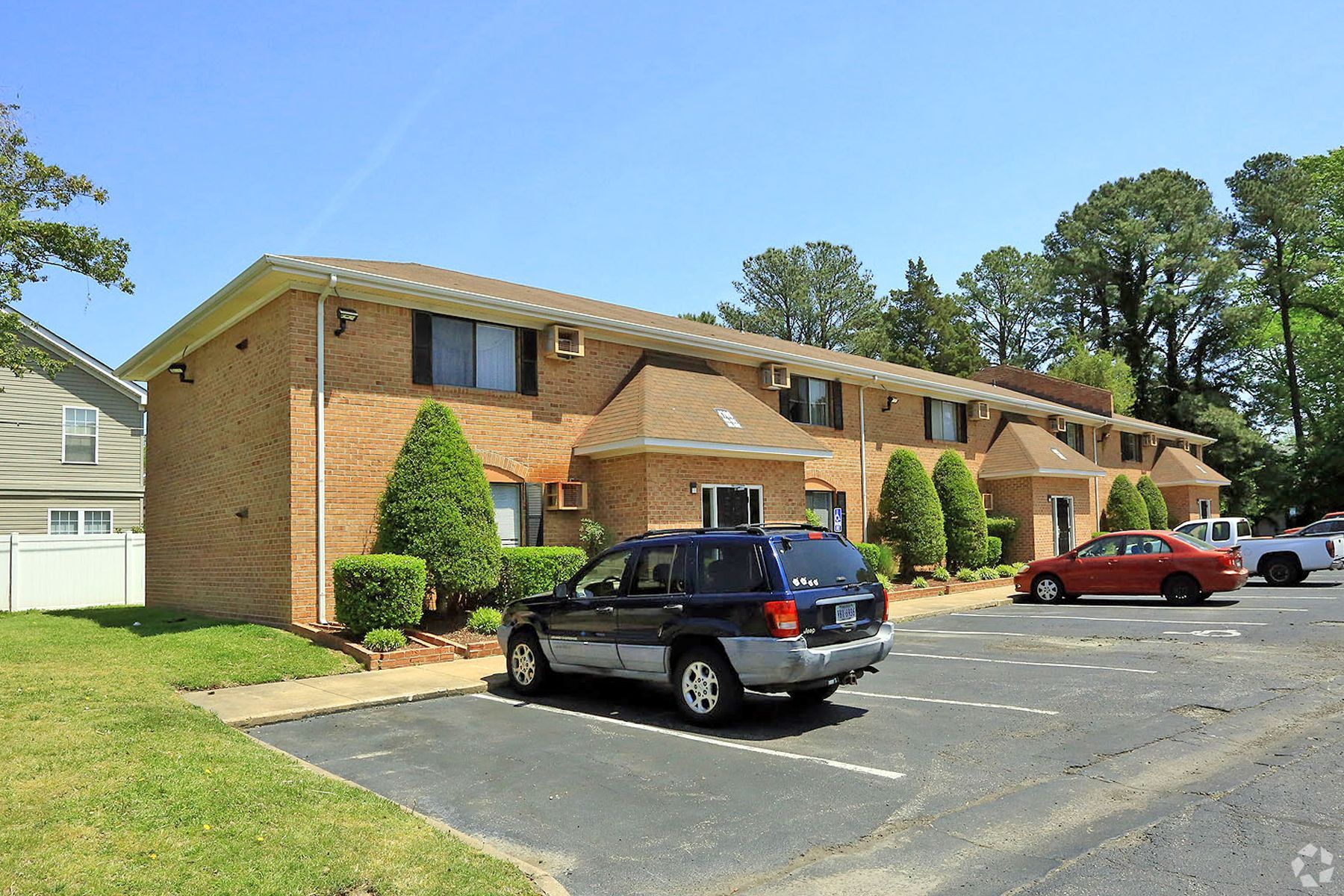 A brick apartment building with cars parked in front of it