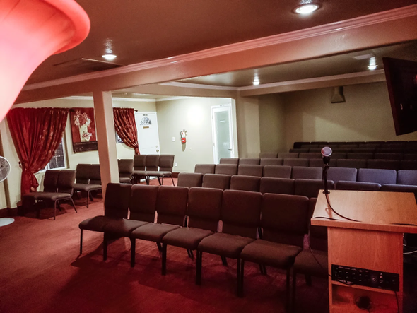 Empty conference room with rows of brown chairs, red carpet, and curtained windows