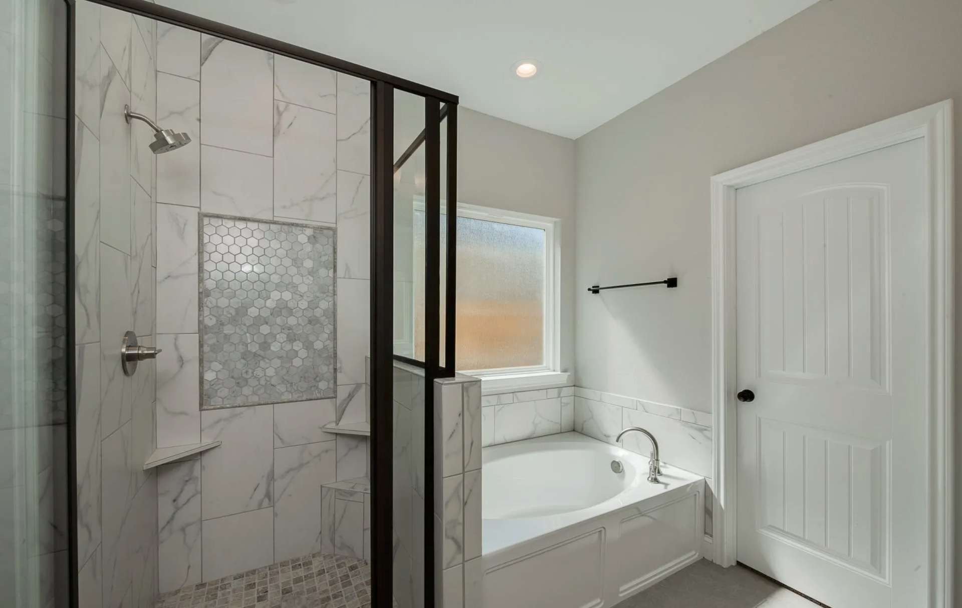 Modern bathroom with white marble shower, tub, and walls; black shower frame and accents.