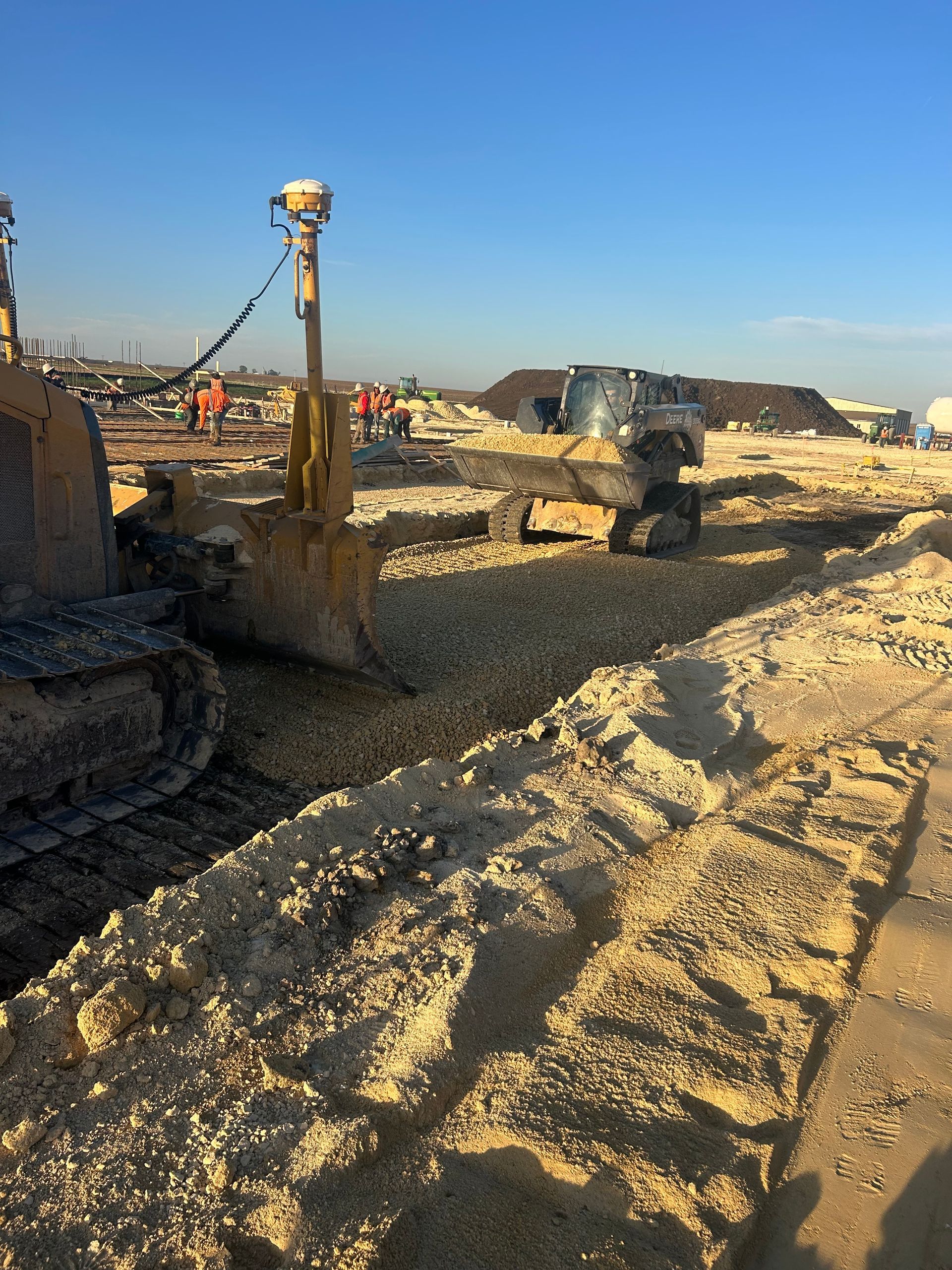 Bulldozer at a sandy construction site under a clear blue sky
