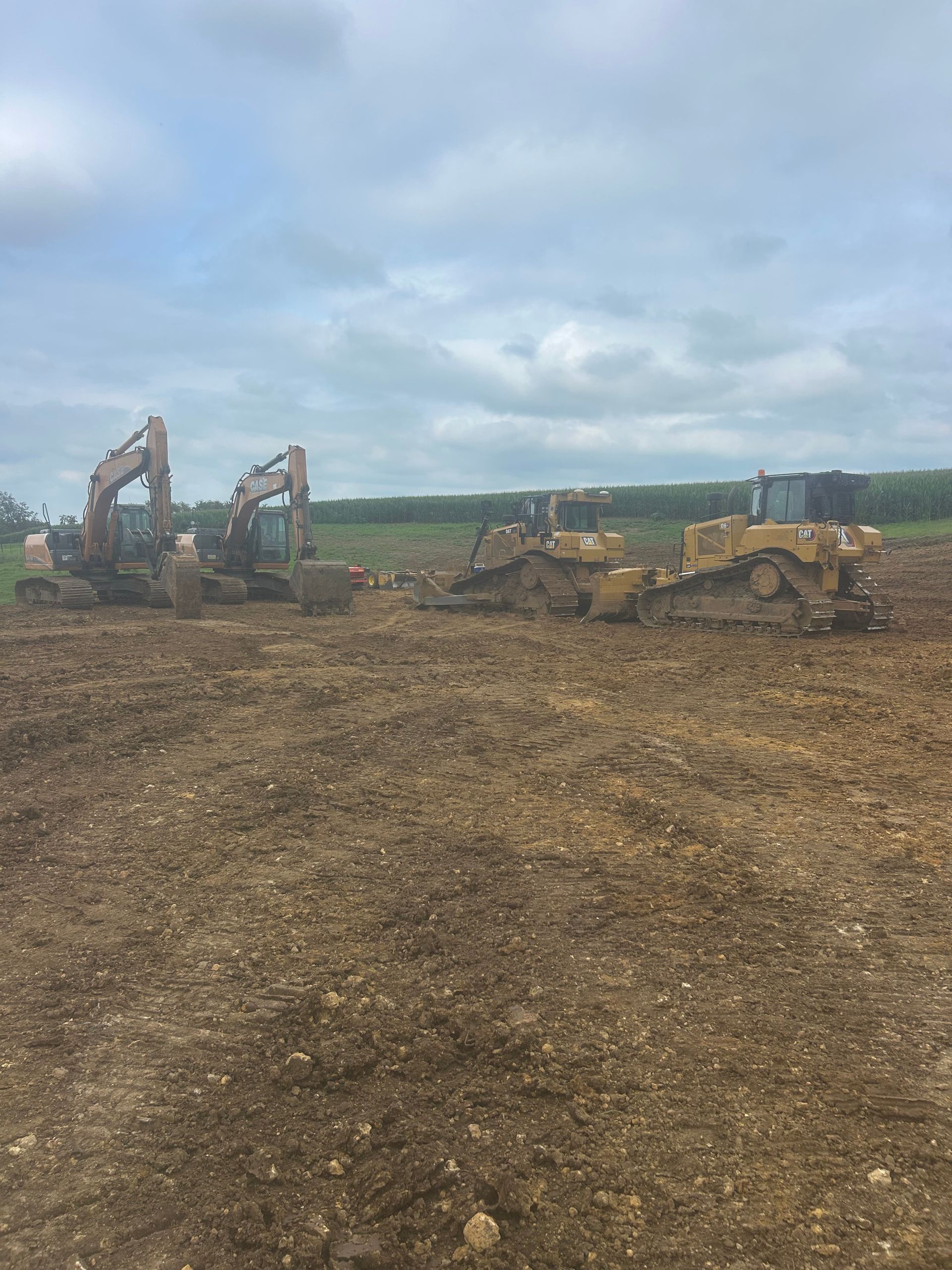 Cleared dirt lot with construction machinery under a cloudy sky