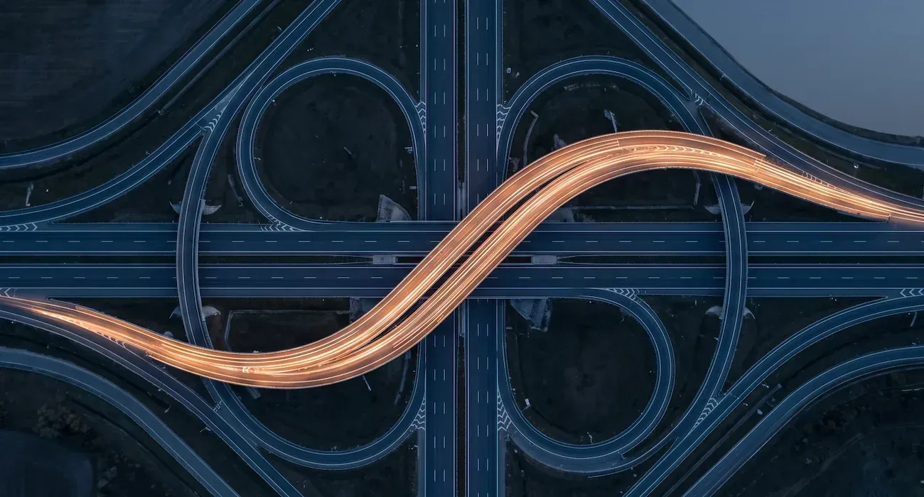 Aerial view of a highway interchange with traffic flowing on one lit lane and others empty.