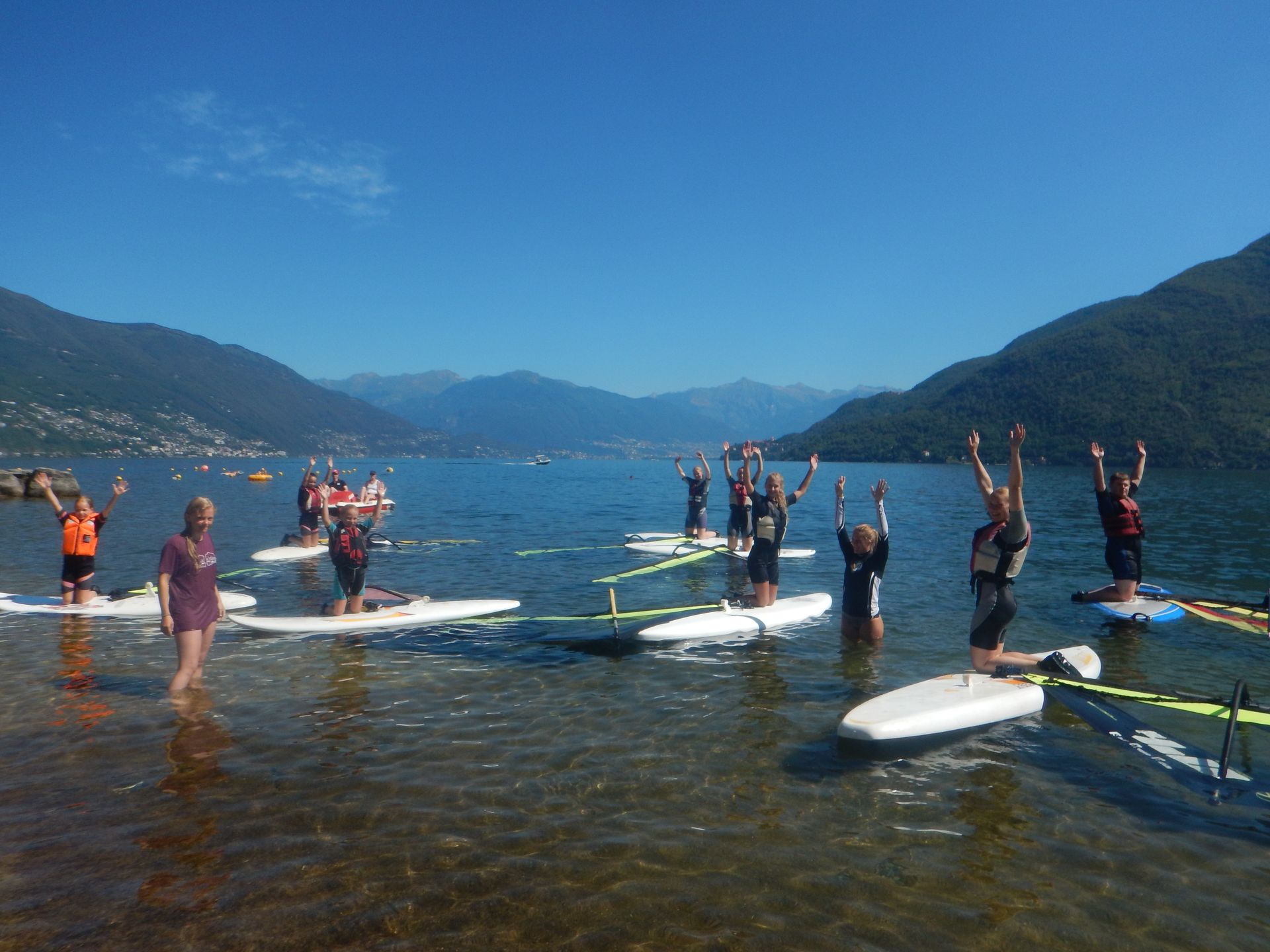 People on paddleboards and kayaks on a calm mountain lake under a blue sky