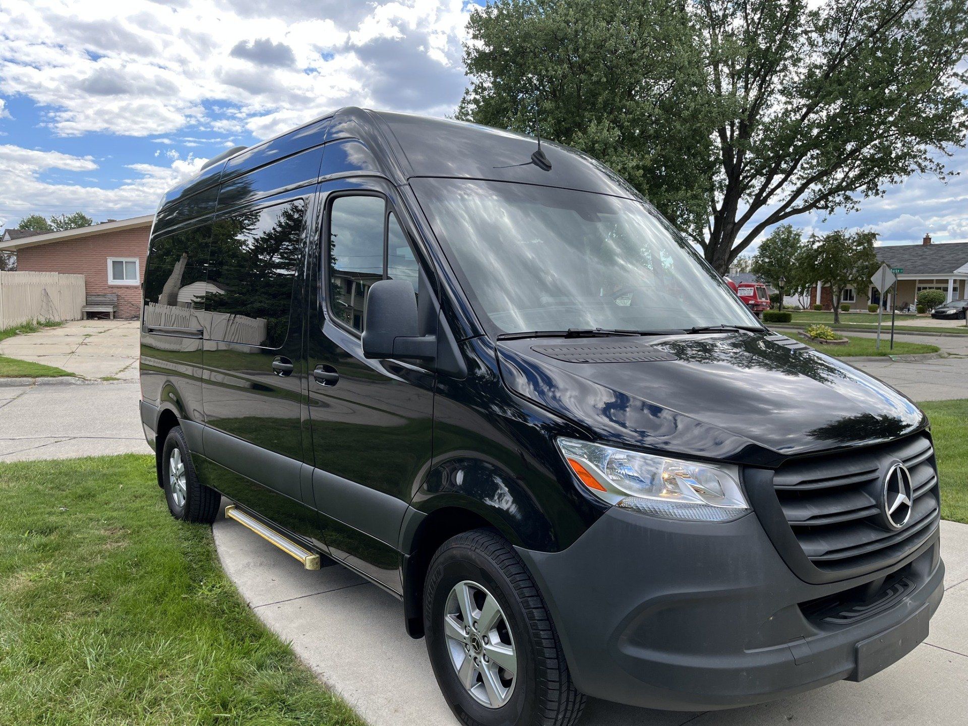 A black mercedes sprinter van is parked in a driveway in front of a house.