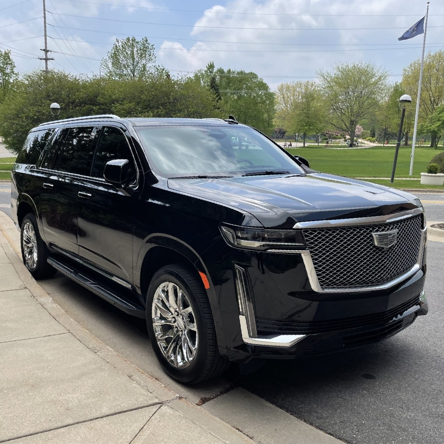 A black cadillac escalade is parked on the side of the road