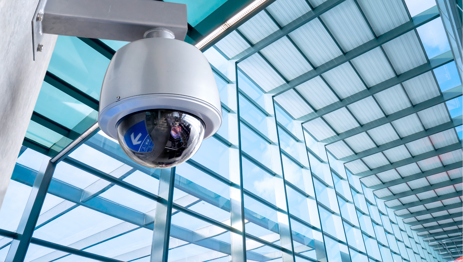 Security camera mounted under a glass roof in a modern building interior