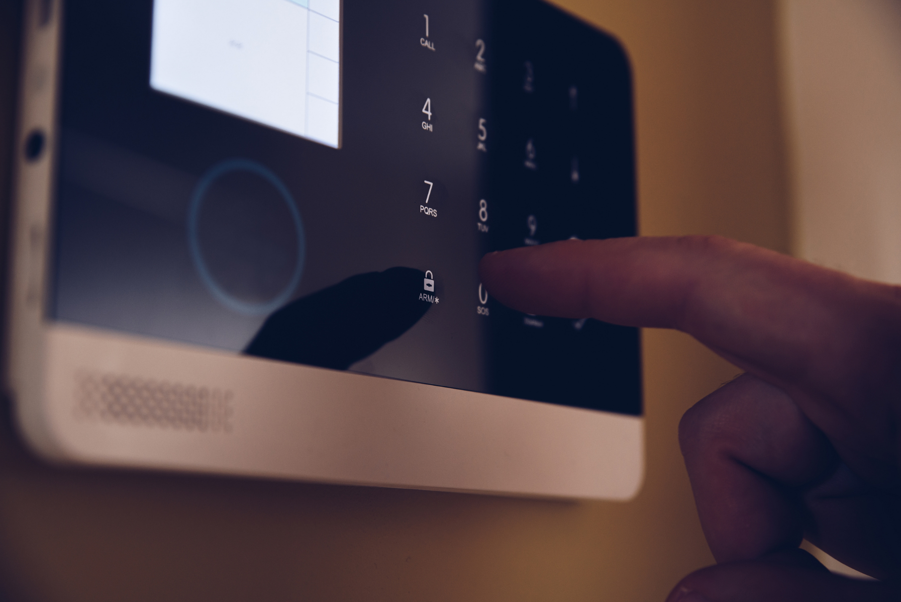 Finger pressing a security keypad on a wall-mounted intercom screen