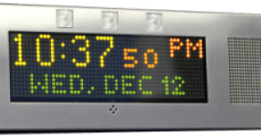 A silver digital clock display showing 10:37:50 PM on Wednesday, December 12th in yellow and green dot-matrix text.