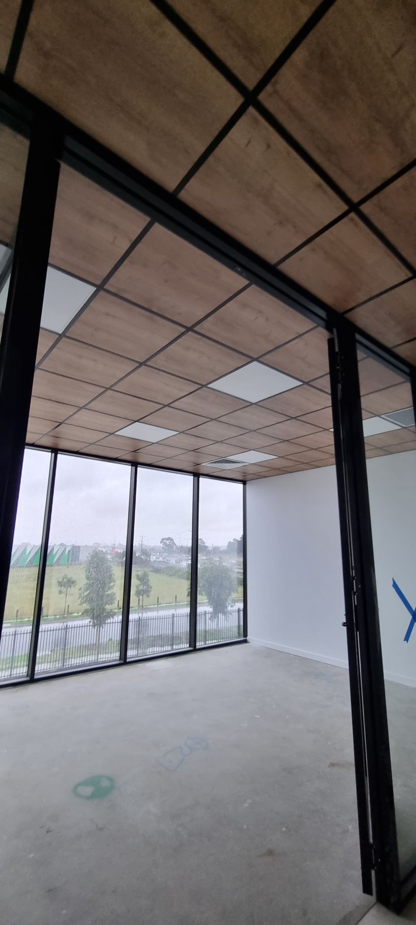 A drop ceiling with a grid of white square LED light panels and circular recessed speakers or sensors. A drop ceiling with a grid of white square LED light panels and circular recessed speakers or sensors.