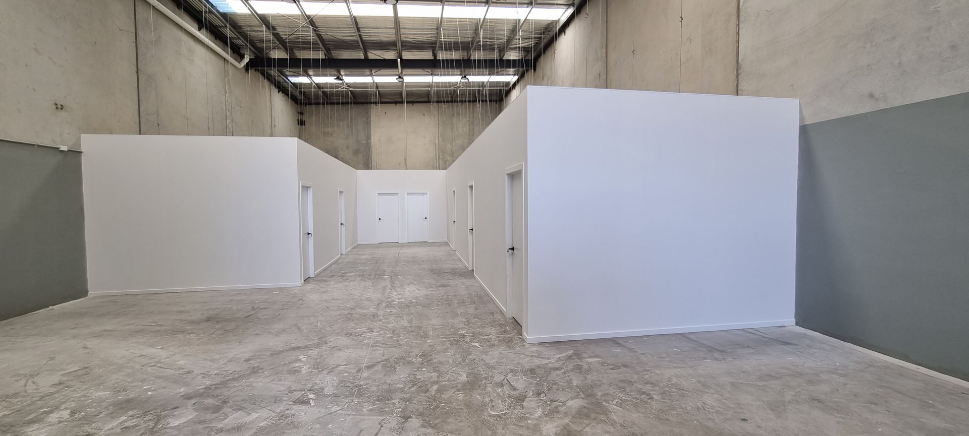 A modern office space with white desks, light-colored chairs, a tablet, and notebooks viewed through glass partitions.