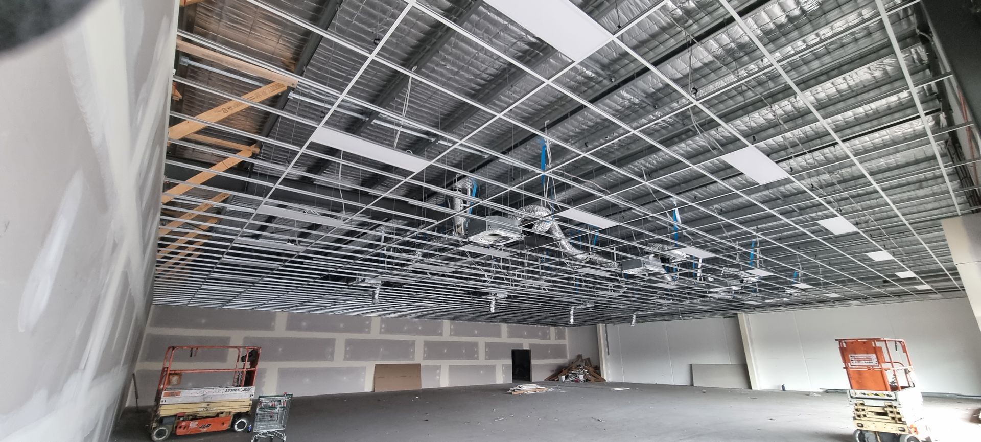 A drop ceiling in an office space with recessed fluorescent lighting fixtures and a central air conditioning vent.