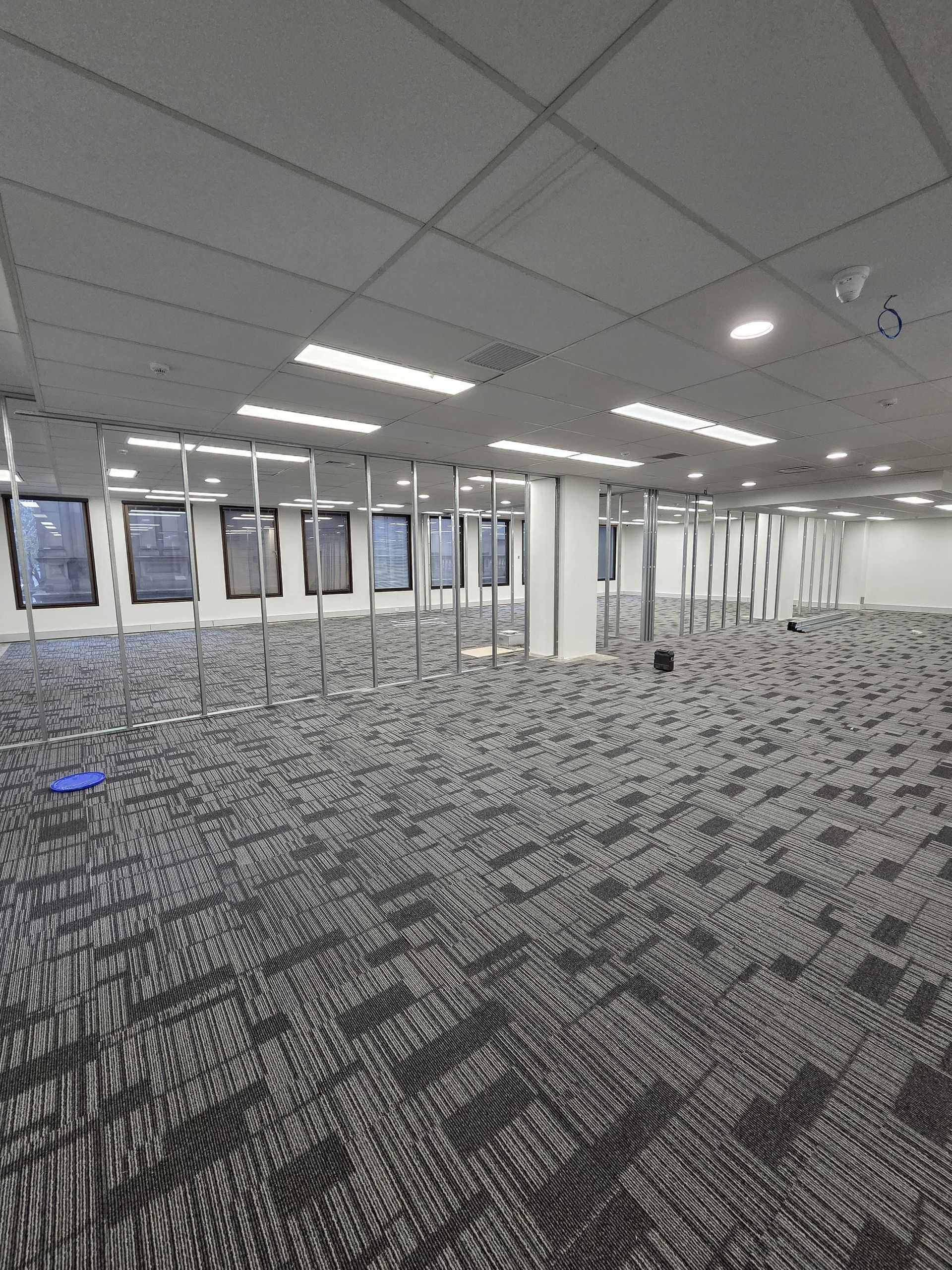 Empty, partitioned office space with missing ceiling tiles showing the infrastructure above.