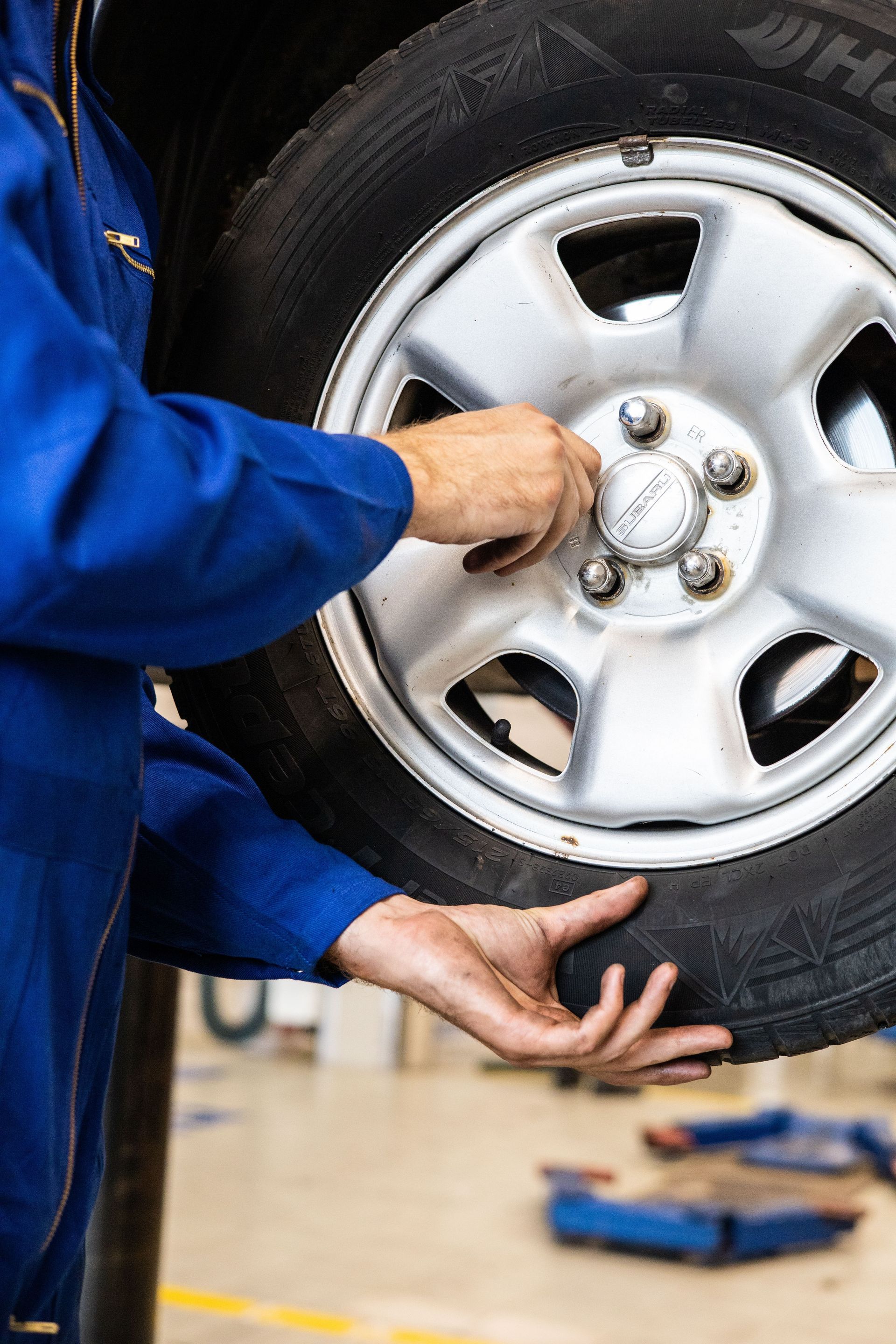 T&eacute;cnico latinoamericano con birlos y tuercas automotrices en taller moderno