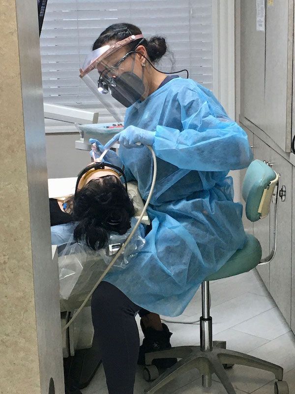 A dentist is examining a patient 's teeth in a dental office.