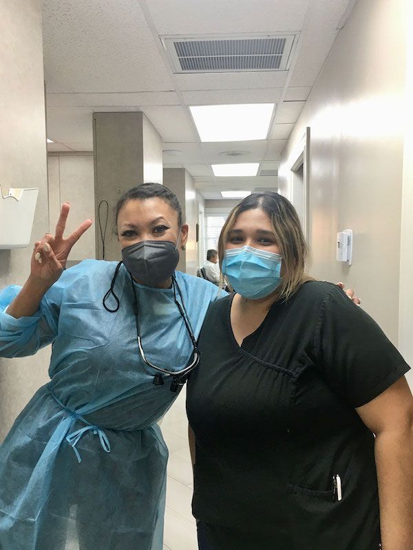 Two women wearing masks are posing for a picture in a hallway.