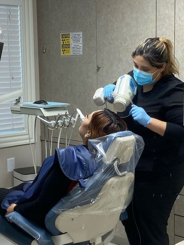 A woman in a dental chair is getting her teeth examined by a dentist.