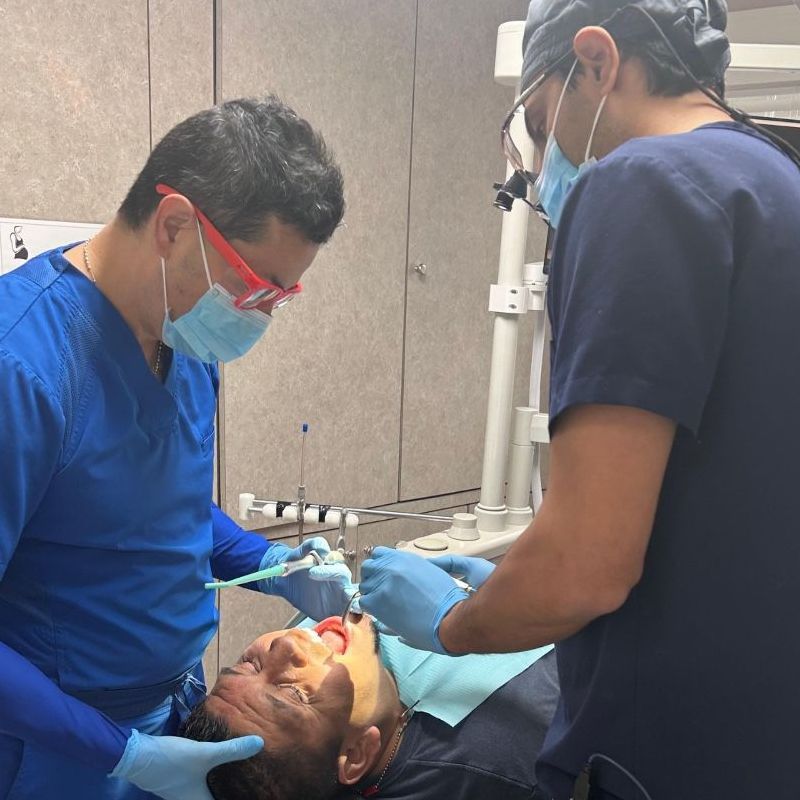 Two dentists are working on a patient in a dental office